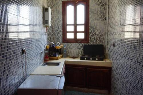 una pequeña cocina con fregadero y ventana en Emallayan Hostel, en Imsouane