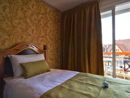 ein Schlafzimmer mit einem Bett und einem großen Fenster in der Unterkunft Résidence Ifrane Palace in Ifrane