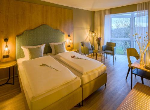 a hotel room with two beds and a table and chairs at Hotel Kammweg in Grossbreitenbach
