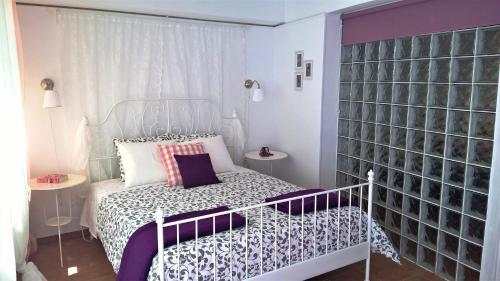 a small bedroom with a white bed with purple sheets at Driopon Apartment in Athens