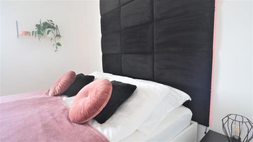 Una cama con almohadas rosas y blancas. en Apartament Silesia, en Zielona Góra