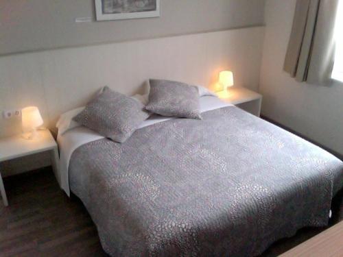a bedroom with a bed with two lights on two tables at Estació Del Nord in Vic