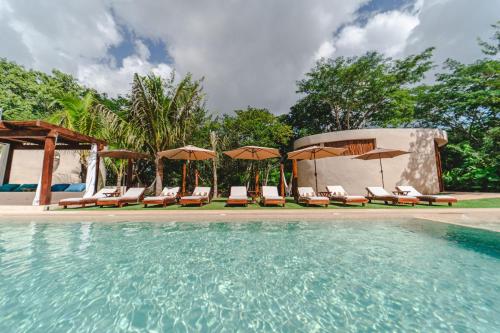 - une piscine avec des chaises longues et des parasols dans l'établissement Destino Mío by AKEN Soul, 