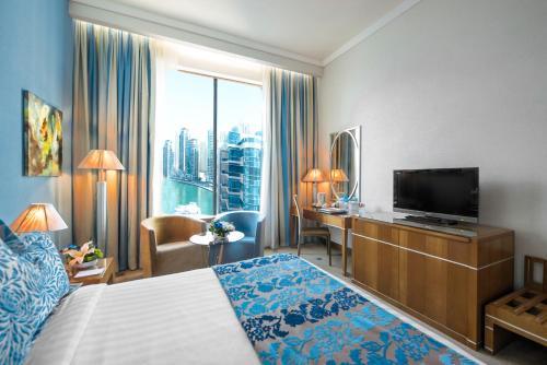 um quarto de hotel com uma cama e uma televisão de ecrã plano em Marina Byblos Hotel no Dubai