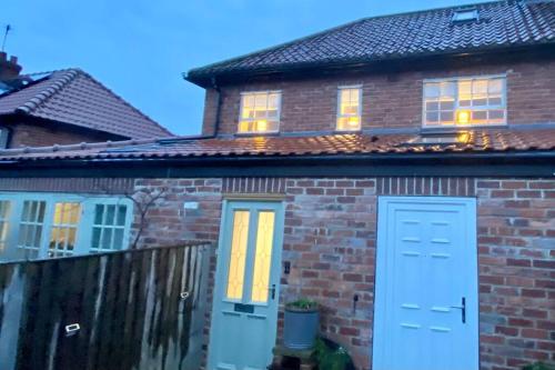 a brick house with blue doors and a fence at Stylish 1st Floor flat Free Parking 2mins from Junction 48A1m in Boroughbridge