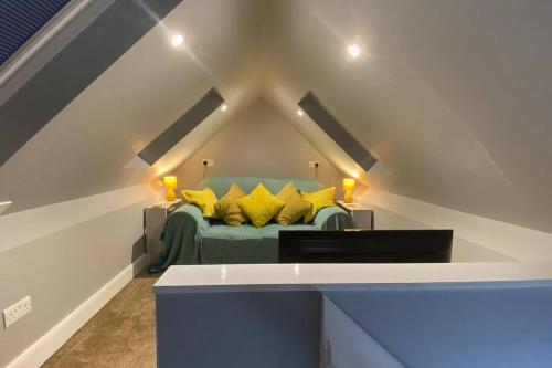 a attic bedroom with a green bed with yellow pillows at Stylish 1st Floor flat Free Parking 2mins from Junction 48A1m in Boroughbridge