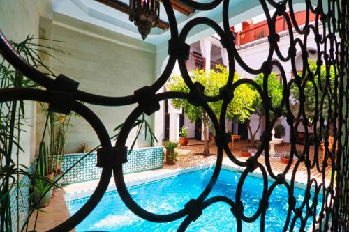 a view of a swimming pool through a metal fence at Riad Al Wifak in Marrakesh