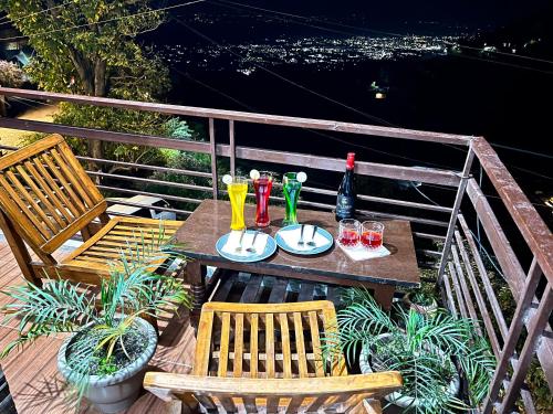 a table with two chairs and drinks on a balcony at Vanshika homes Near mall road in Kasauli