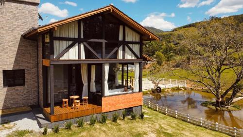a house with a large window next to a river at Alameda dos Ipês, casa completa, para toda família in Santo Amaro da Imperatriz
