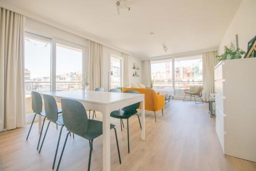 une salle à manger avec une table et des chaises blanches dans l'établissement Between Waves, à Ostende