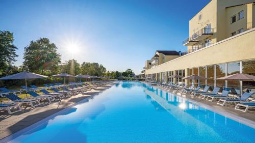 een zwembad met stoelen en parasols naast een gebouw bij Dorint MARC AUREL Spa & Golf Resort in Bad Gögging