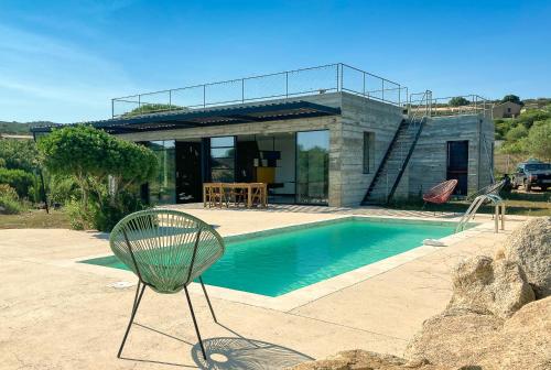 une chaise en face d'une maison avec piscine dans l'établissement Villa esprit moderniste avec piscine, à Bonifacio