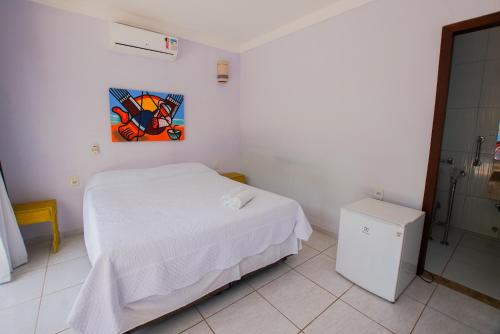 a white bedroom with a bed and a painting on the wall at Xamã Senses - Hotel Pousada in Pipa