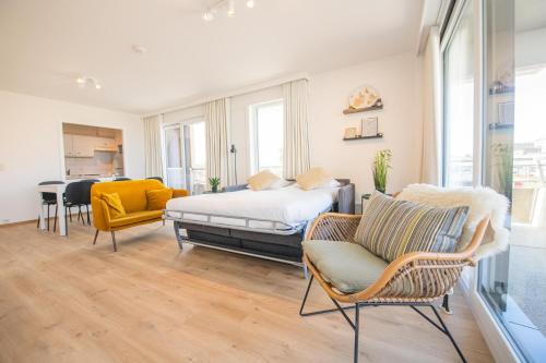 a bedroom with a bed and chairs in it at Between Waves in Ostend