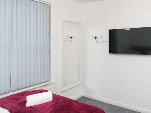 Cette chambre blanche comprend un lit et une télévision. dans l'établissement Excel House Serviced Apartments, à Leeds
