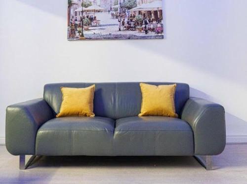 a blue couch with two yellow pillows on it at Excel House Serviced Apartments in Leeds