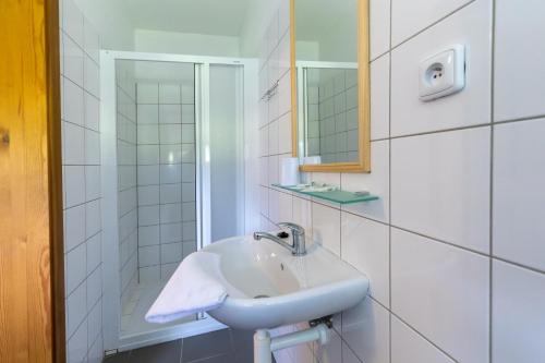 a white bathroom with a sink and a mirror at Hostinec u Zámečku Klokočov in Klokočov