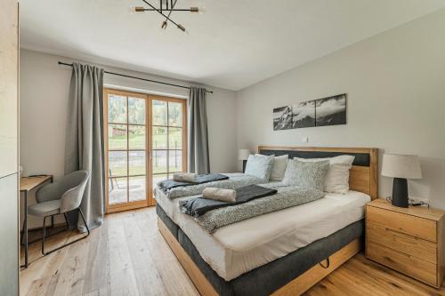 a bedroom with a bed and a desk and a window at Dachstein West Apartment T3 in Russbach am Pass Gschütt