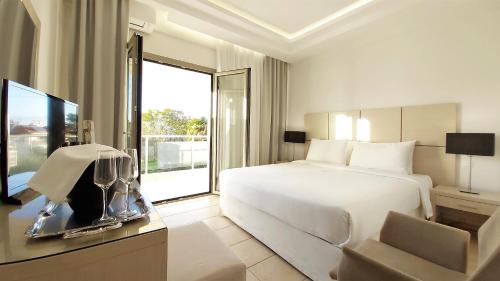 um quarto de hotel com uma cama e uma televisão em Akrogiali Exclusive Hotel (Adults Only) em Polykhrono