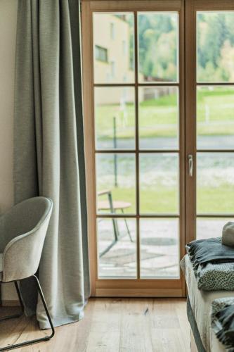 a room with a sliding glass door with a chair at Dachstein West Apartment T3 in Russbach am Pass Gschütt