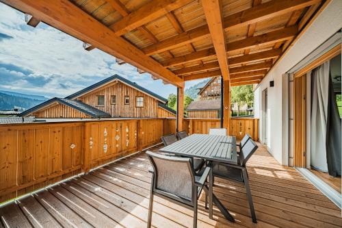 eine Holzterrasse mit einem Tisch und Stühlen darauf in der Unterkunft Dachstein West Apartment T3 in Russbach am Pass Gschütt