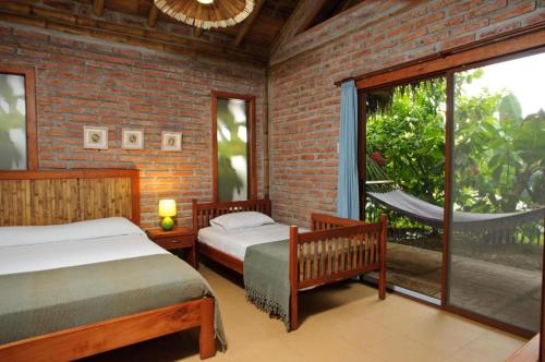 a bedroom with two beds and a large window at El Campito Lodge in Ayampe