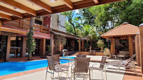 an outdoor patio with a table and chairs next to a swimming pool at Pousada Sonho Meu Foz in Foz do Iguaçu