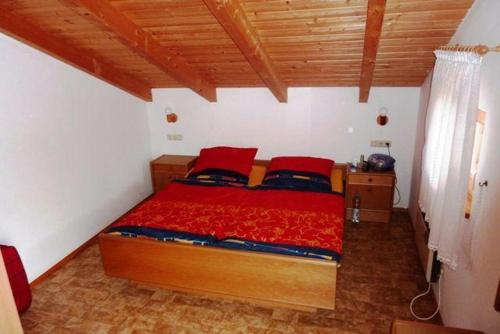 レーゲンにあるHaus-am-Waldのベッドルーム1室(木製ベッド1台、赤い枕付)
