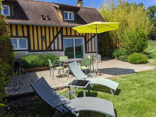 eine Terrasse mit einem Tisch, Stühlen und einem Sonnenschirm in der Unterkunft Domaine du Martinaa in Saint-Martin-de-la-Lieue