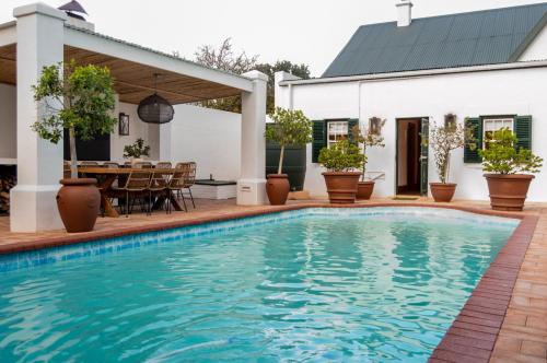 a swimming pool in front of a house with a table and chairs at Killassy House in Graaff-Reinet