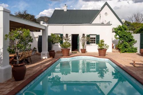 a swimming pool in front of a white house at Killassy House in Graaff-Reinet