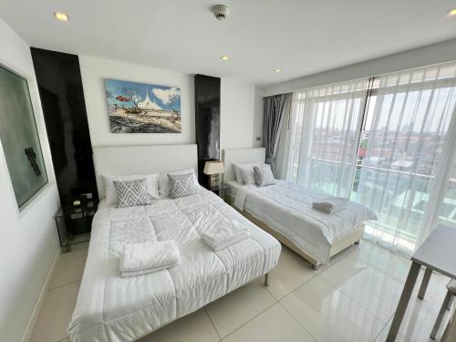 a bedroom with two beds and a large window at TRENDY Studio in City Center Residence in Pattaya