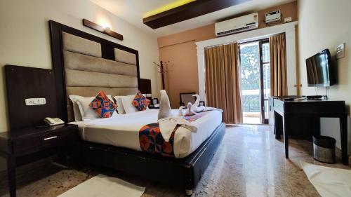 a bedroom with a bed and a desk and a television at Crystal Paark Inn By Blu Orchid Group in Mysore