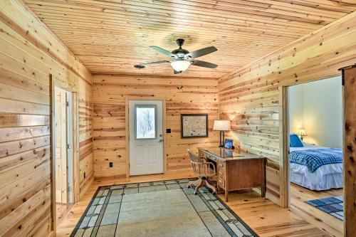 a log cabin bedroom with a desk and a ceiling fan at Breathtaking Elkin Getaway with Vineyard Views! in Elkin
