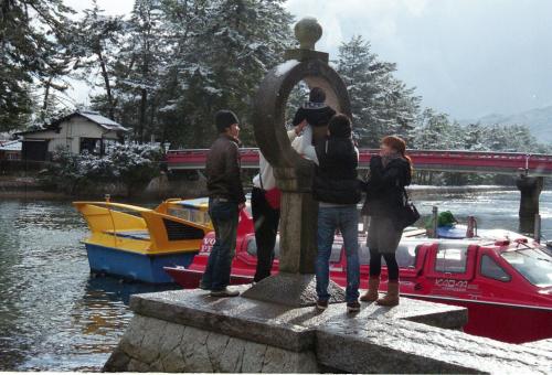 a group of people standing around a statue next to a boat at Taikyourou in Miyazu