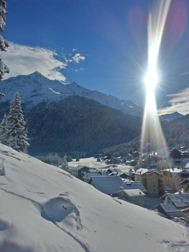 a town in the snow with the sun shining at Hotel Nordik in Santa Caterina Valfurva
