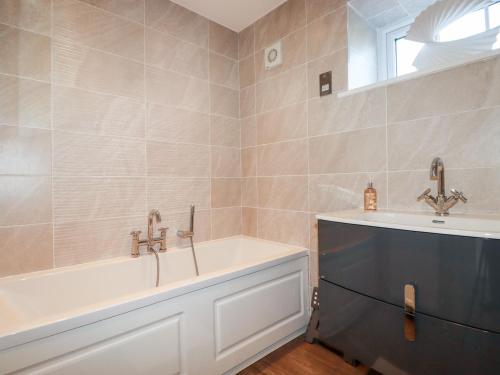 a bathroom with a bath tub and a sink at Great Meadow Barn in Newquay