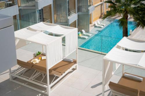 a white house with a swimming pool and a table and chairs at Reverence Mare Hotel - Adults Only in Palmanova
