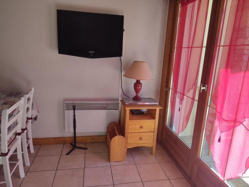 une chambre avec une télévision et une table avec une lampe dans l'établissement Boost Your Immo Les Deux Alpes Chalets d'or 792, à Les Deux Alpes