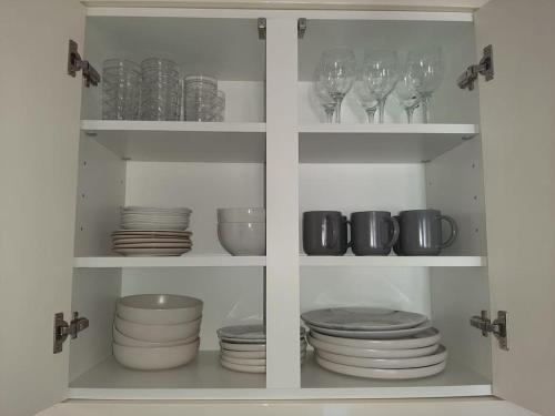 a white cabinet filled with plates and wine glasses at Huge Garden House for Contractors and Families in Ollerton