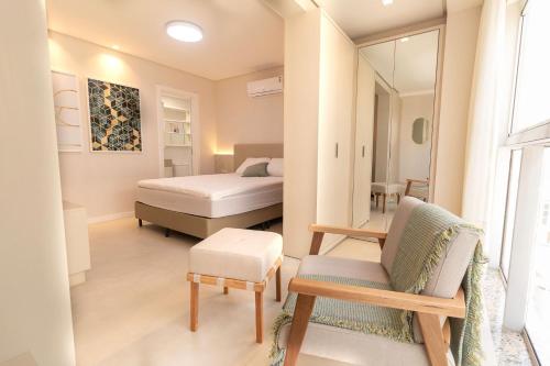 1 dormitorio con cama, silla y espejo en Puntarenas 304 - Excelente cobertura duplex 2 suítes - Finamente mobiliada e decorada - À poucos metros da praia, en Bombinhas