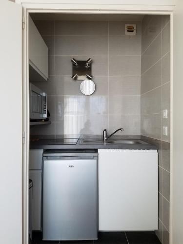 - une cuisine avec 2 placards blancs et un évier dans l'établissement Studio au calme, Parking, proche Thermes, à Aix-les-Bains