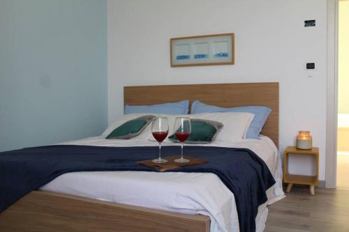 a bedroom with two glasses of wine on a bed at Appartamento incantevole con piscina in Cervo