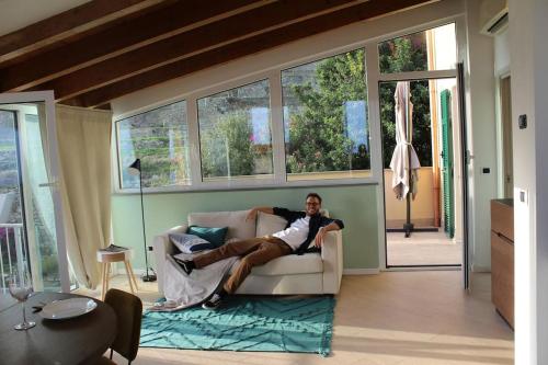 a man sitting on a couch in a living room at Appartamento romantico con piscina in Cervo