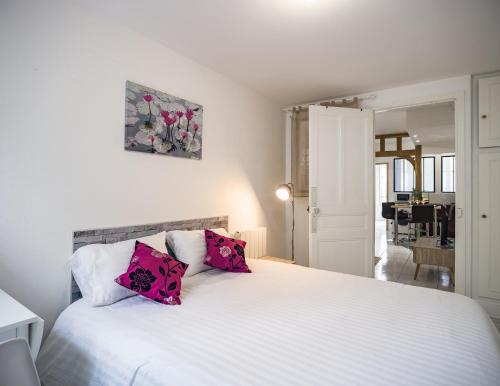 una camera da letto con un letto bianco e cuscini rosa di Le Colombage-3 chambres- Hypercentre a Troyes