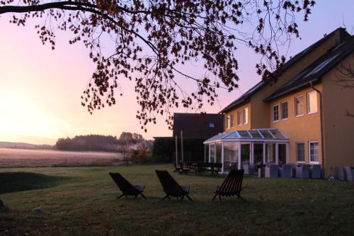 a group of chairs sitting in the grass in front of a house at Hotel am Müritz-Nationalpark in Waren