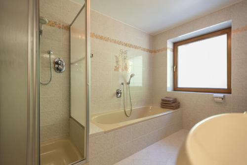 y baño con ducha, bañera y lavamanos. en Pixnerhof - Ferienwohnung Golden en Ciardes