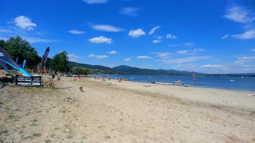 a beach with a bunch of people on it at Apartament z Tężnią Solankową, Sauną, Kominkiem LED i Śniadaniem nad Jeziorem Żywieckim in Zarzecze