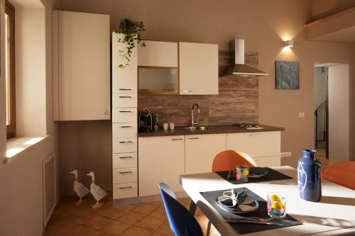 a kitchen with white cabinets and a table and chairs at SeiPetali in Cannara