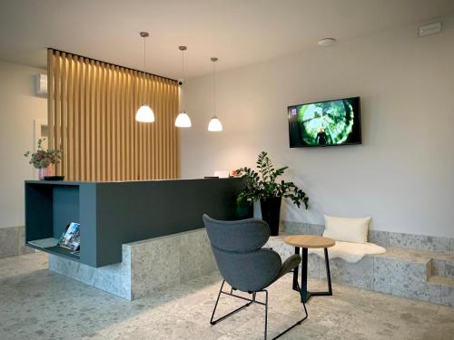 vestíbulo con silla y TV en la pared en Guest house Stara lipa Tašner - free parking & kitchenette, en Maribor